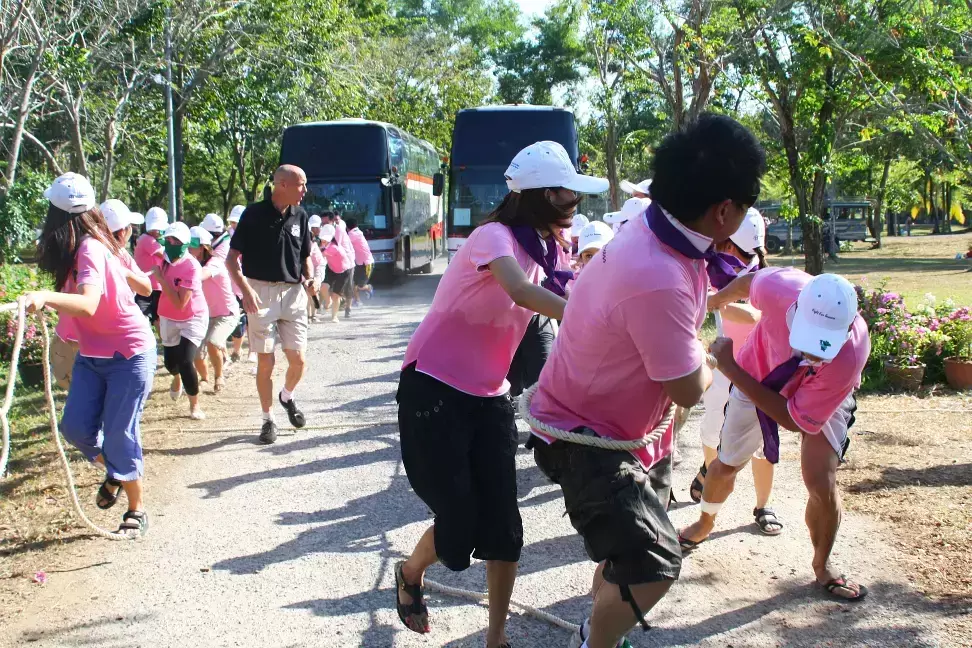 Virtual Minister leading a team building activity with 2 teams of ladies in pink shirts pulling 2 big coaches in a race.
