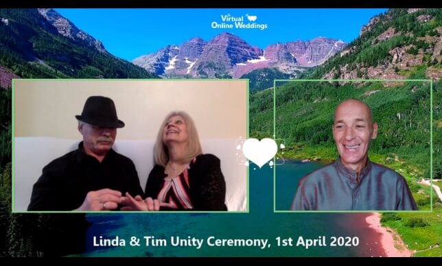 Virtual Celebrant performing online Renewal of Vows ceremony for late middle aged couple on their sofa in room, with Colorado mountains background photo.